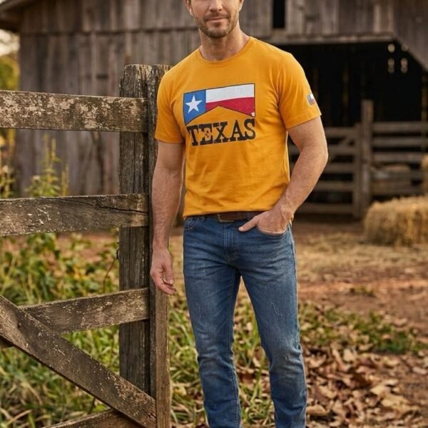 Homem de camiseta mostarda Lone Star Texas com bandeira do Texas no peito, ao lado do curral